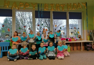 Dzieci trzymają w rękach niebieskie serduszka- świętowanie Happy Brithday.